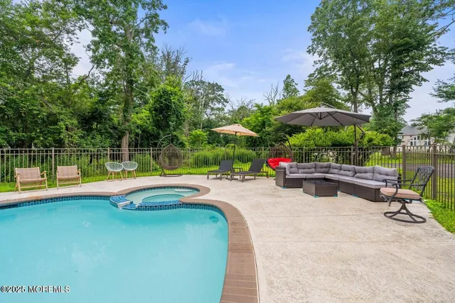 a view of a swimming pool with a bench and trees in the background