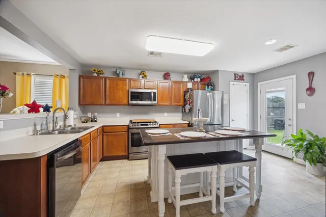 a kitchen with a stove a sink dishwasher a oven with a dining table and chairs