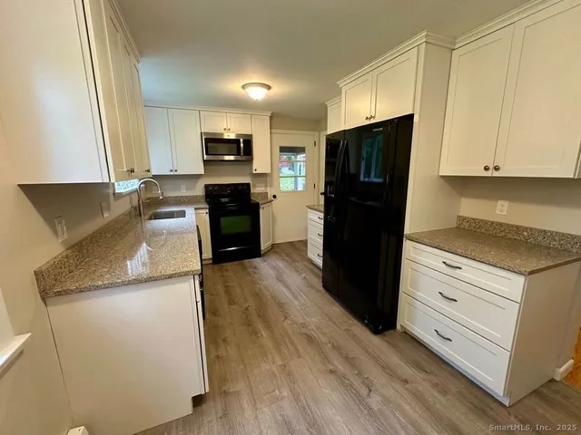 a kitchen with granite countertop stainless steel appliances a refrigerator a stove a microwave and cabinets