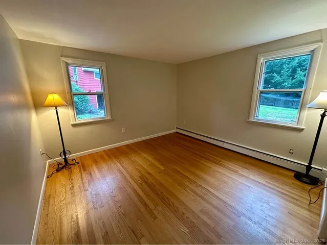 a view of a room with wooden floor mirror and windows