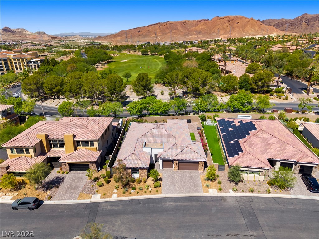 45 Garibaldi Way Henderson, NV 89011 - Photo 40 of 74 An aerial perspective reveals multiple properties with golf course and mountain views under a clear sky.