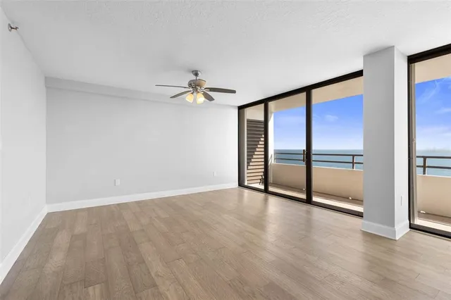 an empty room with wooden floor fan and windows
