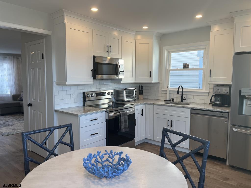 136 44th Street South, Unit A Brigantine, NJ 08203 - Photo 14 of 19 a kitchen with stainless steel appliances granite countertop a sink a stove a microwave a dining table and chairs