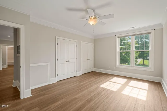 an empty room with wooden floor fan and windows