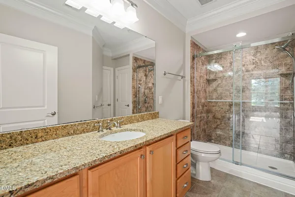 a bathroom with a granite countertop sink a toilet a mirror and shower