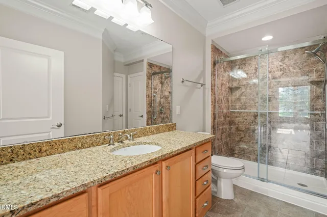 a bathroom with a granite countertop sink a toilet a mirror and shower