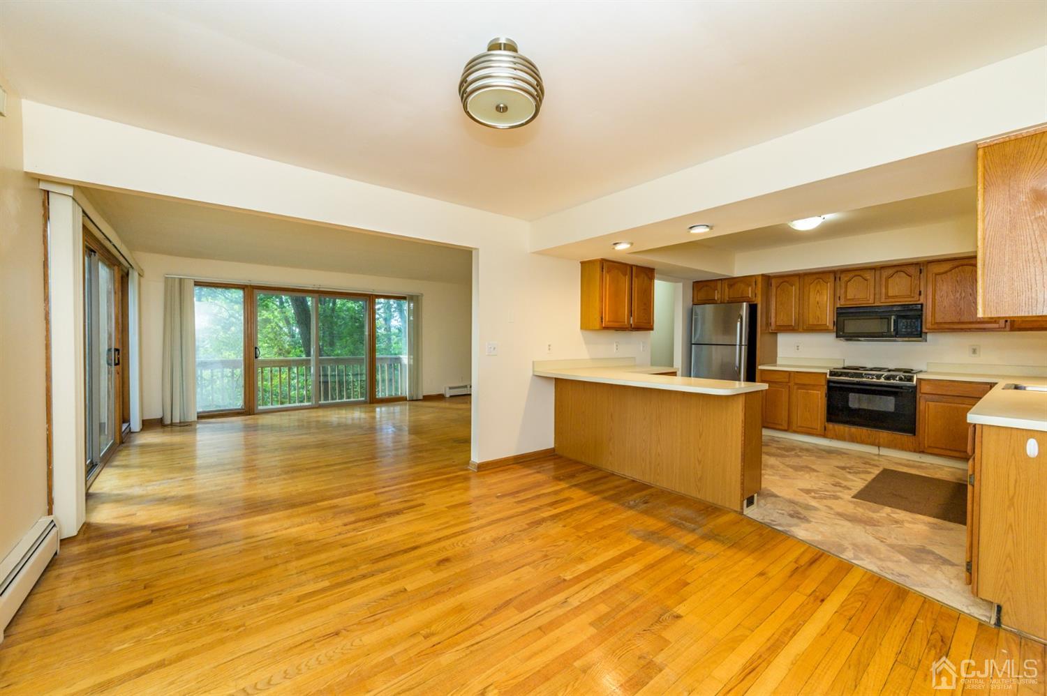 58 Forest Road Andover, NJ 07821 - Photo 11 of 34 a view of a kitchen with kitchen island a sink wooden floor and a large window