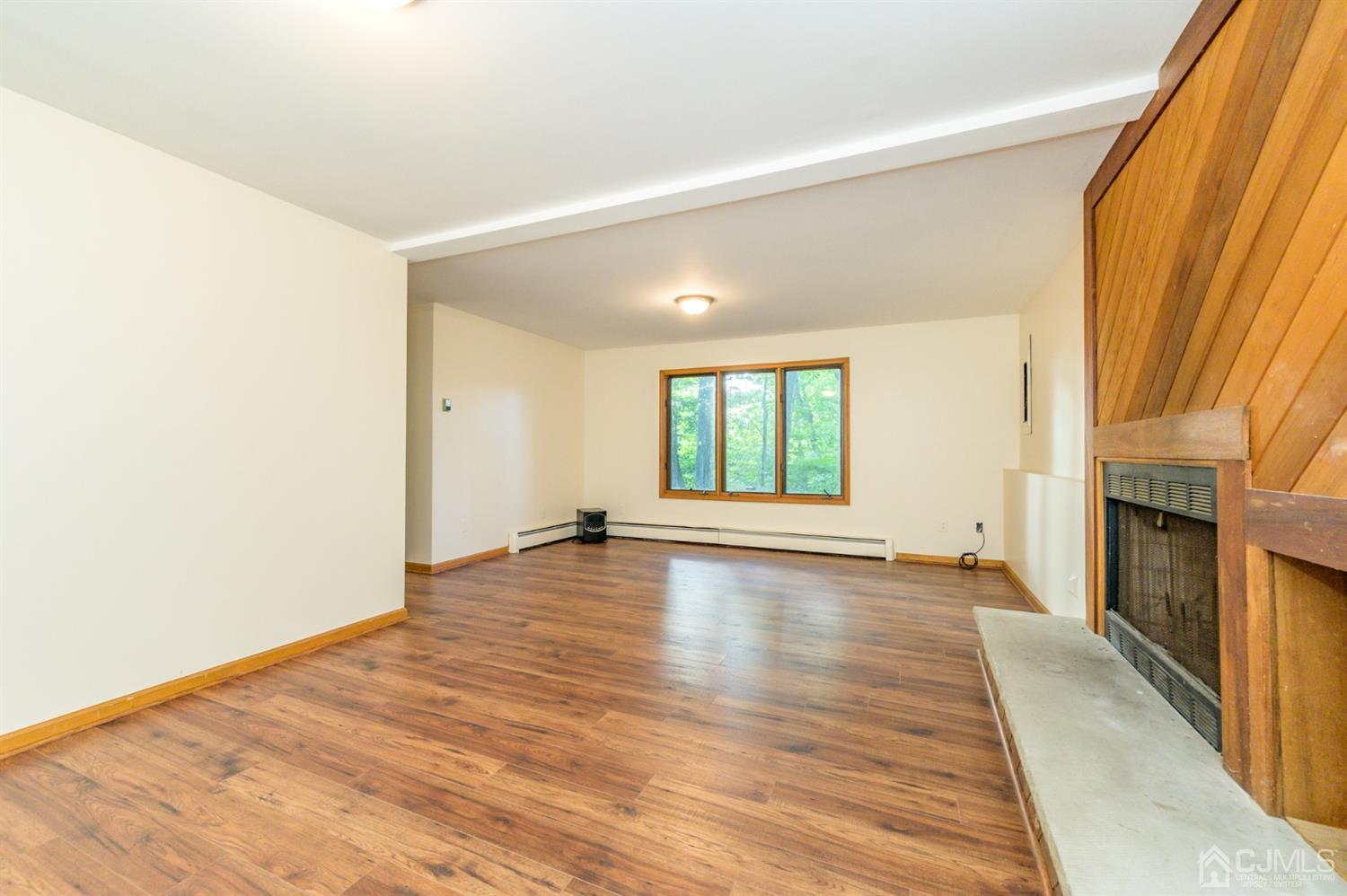 58 Forest Road Andover, NJ 07821 - Photo 5 of 34 an empty room with wooden floor and fireplace