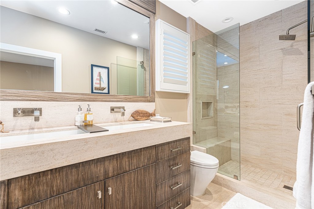 213 34th Street Newport Beach, CA 92663 - Photo 22 of 32 a bathroom with a granite countertop sink toilet a mirror and shower