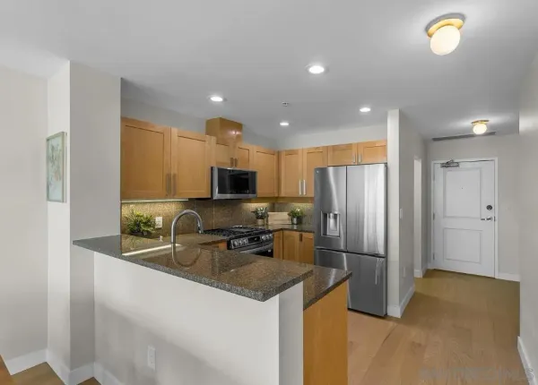 a kitchen with stainless steel appliances granite countertop a refrigerator a stove a sink and a microwave