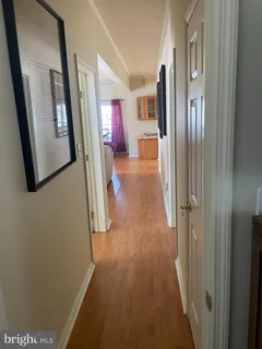 a view of a hallway with wooden floor and livingroom