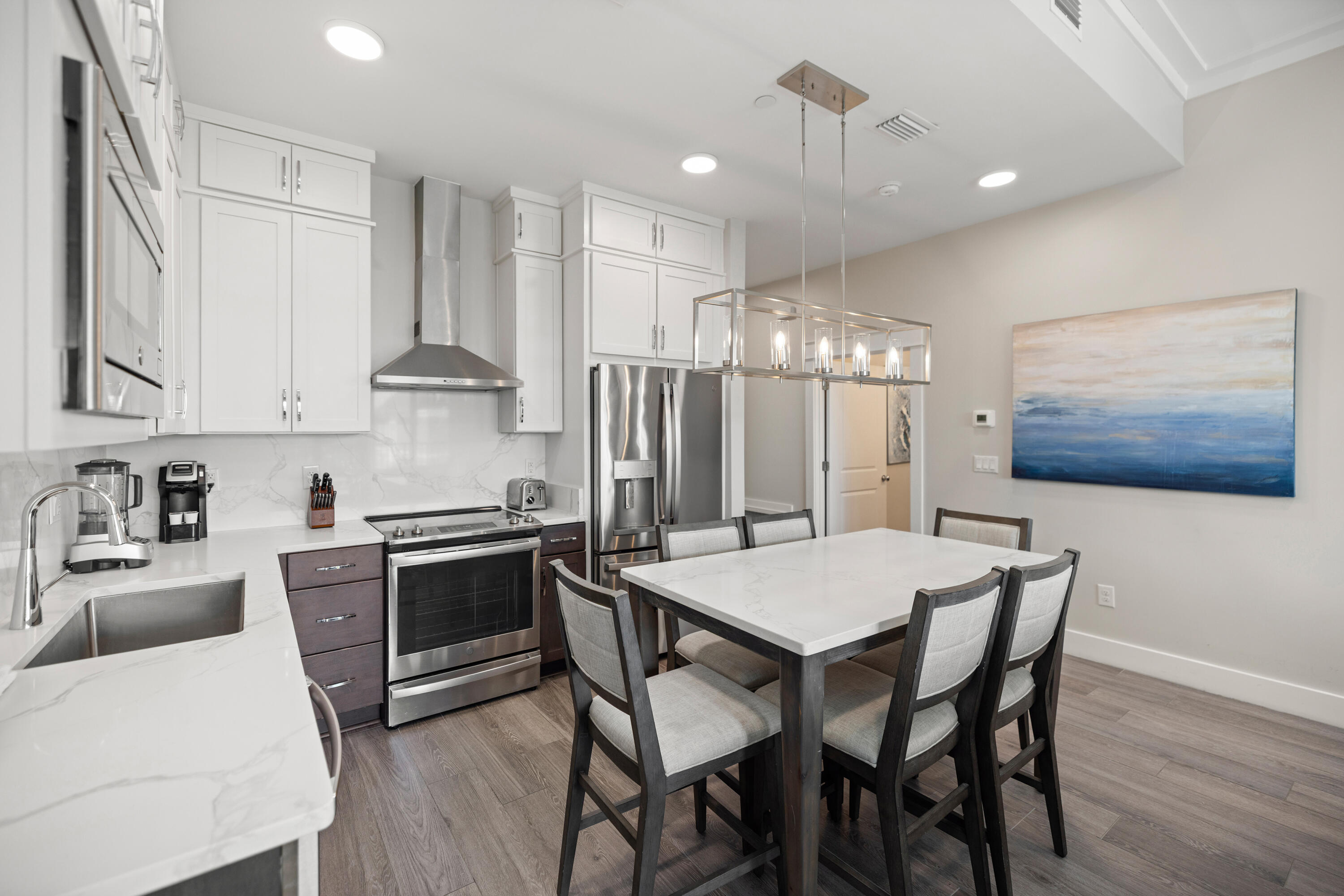 201 Henderson Resort Way, Unit 2202 Destin, FL 32541 - Photo 11 of 48 a kitchen with stainless steel appliances granite countertop a stove a refrigerator a kitchen island a dining table and chairs with wooden floor