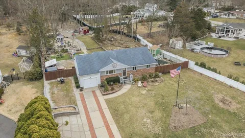 an aerial view of a house with swimming pool and large trees
