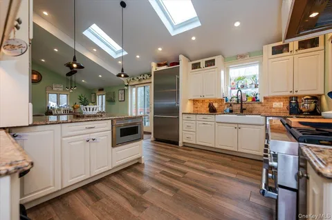 a kitchen with stainless steel appliances a refrigerator a sink a stove and white cabinets