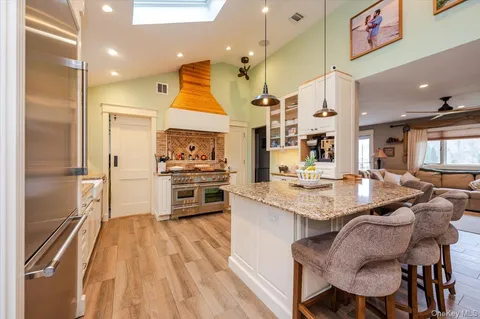 a kitchen with stainless steel appliances kitchen island granite countertop a table chairs in it and wooden floors