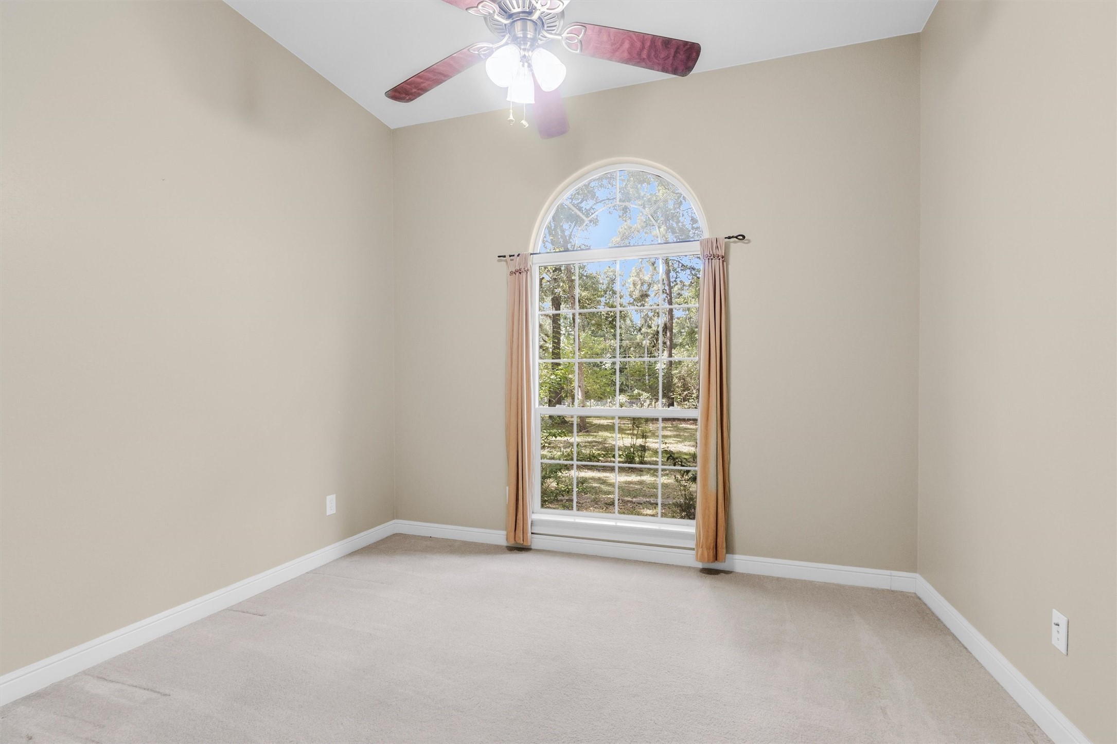 10331 Iron Ore Road Conroe, TX 77303 - Photo 20 of 47 Bright room with high ceilings, a large arched window allowing natural light, and a ceiling fan for comfort.