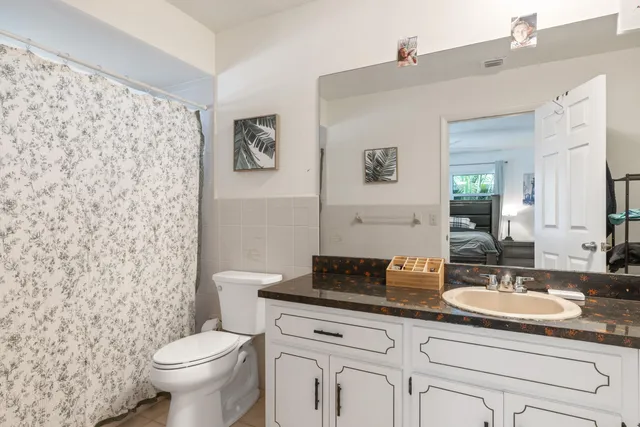 a bathroom with a granite countertop toilet sink and mirror