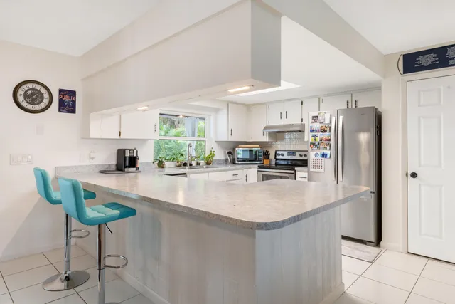 a kitchen with stainless steel appliances granite countertop a refrigerator a stove and a sink