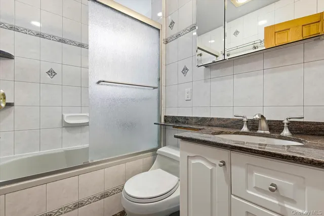 a bathroom with a granite countertop sink a toilet and shower