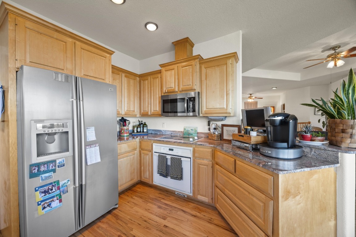 515 Coventry Road Spicewood, TX 78669 - Photo 17 of 36 a kitchen with stainless steel appliances granite countertop a refrigerator a stove top oven a sink and dishwasher