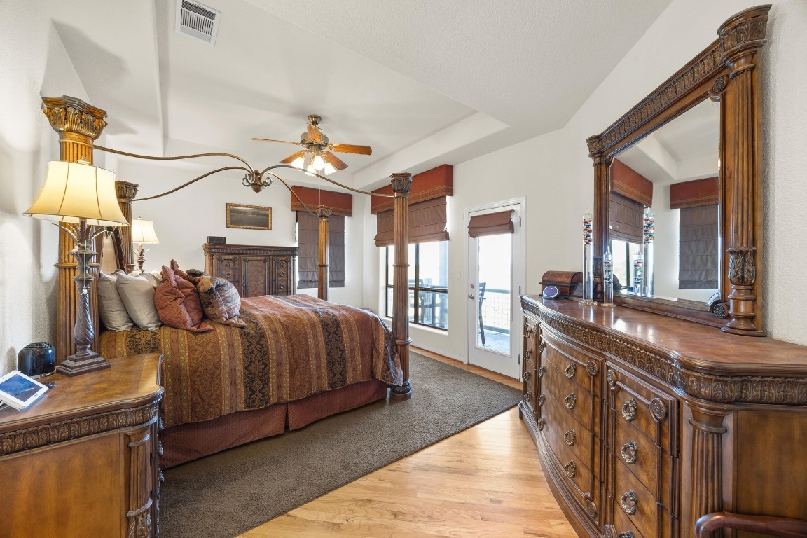 515 Coventry Road Spicewood, TX 78669 - Photo 19 of 36 a spacious bedroom with a bed and a chandelier