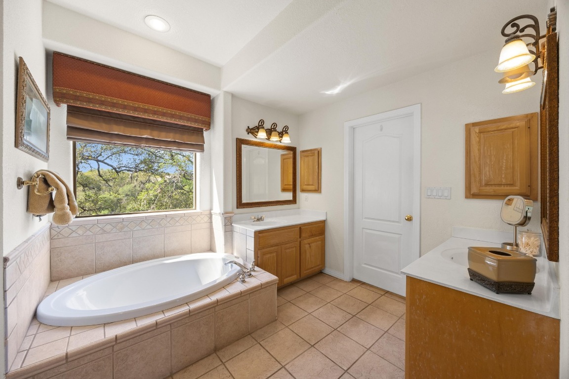 515 Coventry Road Spicewood, TX 78669 - Photo 20 of 36 a bathroom with a bathtub sink and mirror