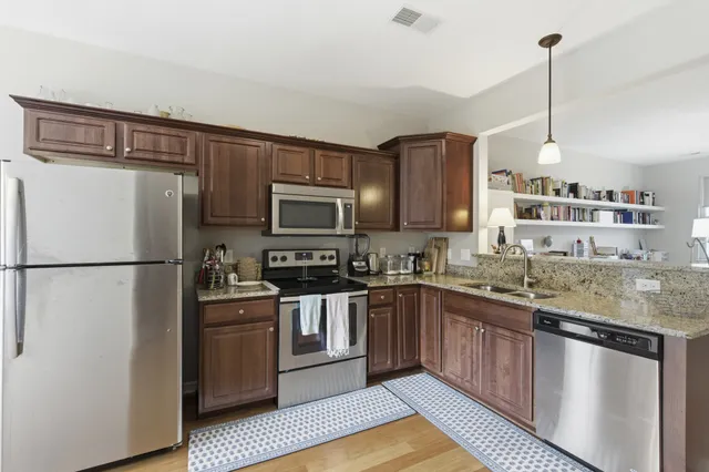 a kitchen with stainless steel appliances granite countertop a refrigerator a stove a sink dishwasher and a microwave