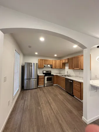 a kitchen with stainless steel appliances granite countertop a refrigerator a sink a stove and oven a oven with wooden floor