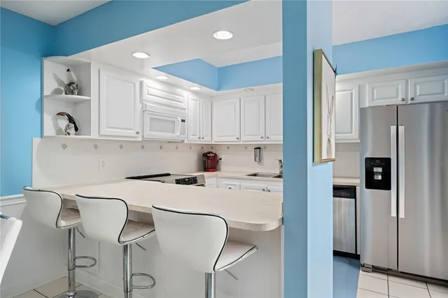 a kitchen with stainless steel appliances a refrigerator a stove a sink and white cabinets with wooden floor