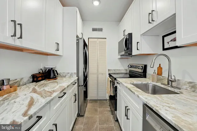a kitchen with granite countertop a sink stainless steel appliances and cabinets