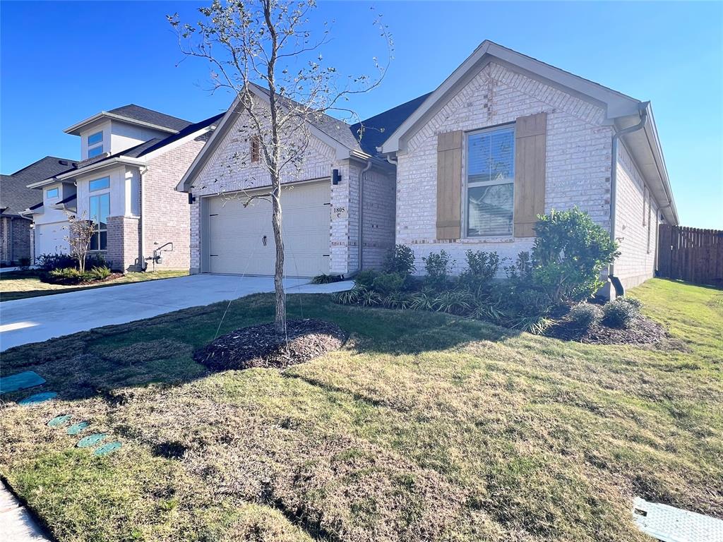 View of front facade with brick siding, driveway, an attached garage, and a front yard