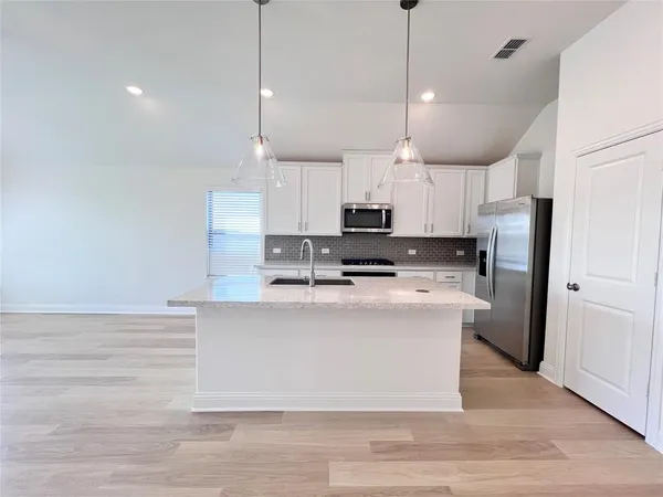 a large kitchen with white cabinets stainless steel appliances and a center island