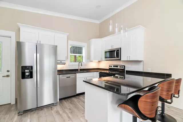 a kitchen with granite countertop white cabinets appliances and a window