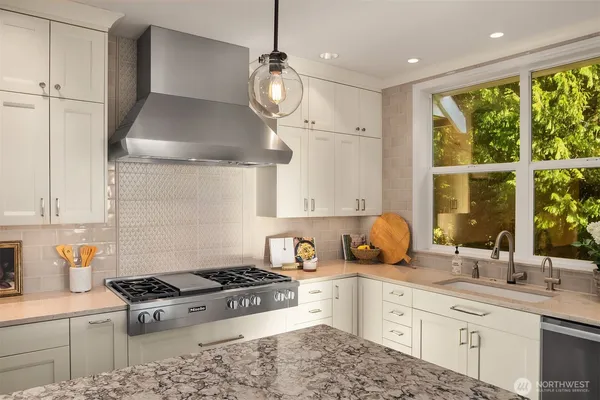 a kitchen with stainless steel appliances kitchen island granite countertop a table chairs and a wooden floor