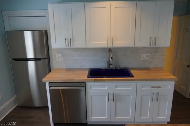 a kitchen with a sink a refrigerator and cabinets