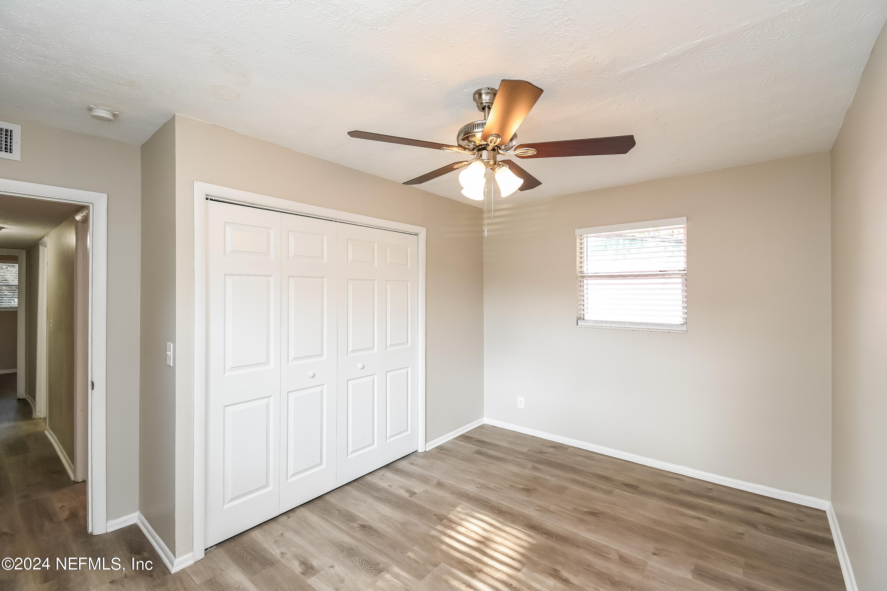 7217 Eudine Drive South Jacksonville, FL 32210 - Photo 10 of 16 an empty room with wooden floor fan and windows