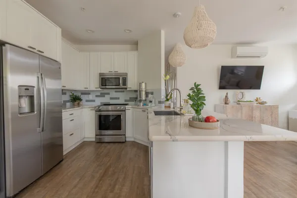 a kitchen with stainless steel appliances a stove a sink dishwasher a refrigerator and a microwave oven with wooden floor