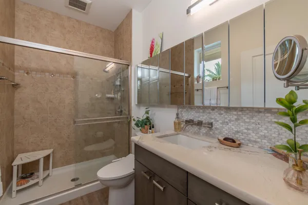a bathroom with a granite countertop sink a toilet and shower