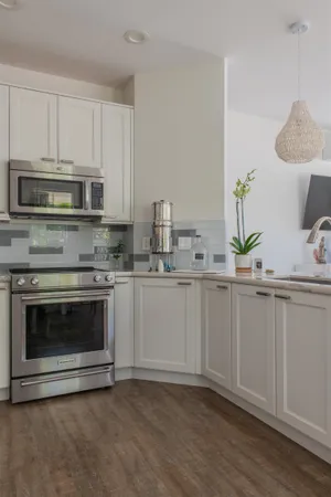 a kitchen with white cabinets stainless steel appliances and wooden floor