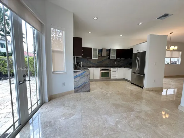 a view of kitchen with stainless steel appliances kitchen island granite countertop a refrigerator and cabinets