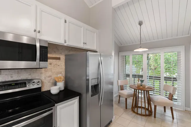 a kitchen with stainless steel appliances granite countertop a stove a refrigerator a dining table and chairs