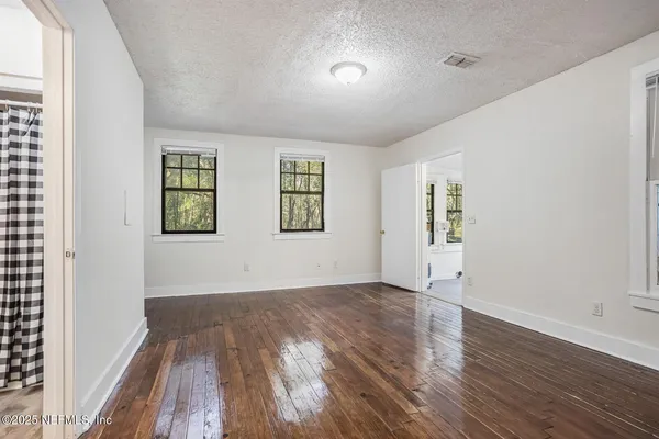 an empty room with wooden floor and windows