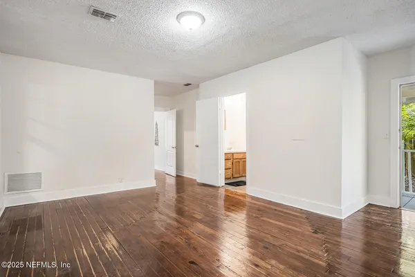 a view of an empty room with wooden floor