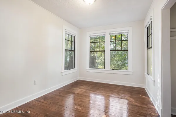 an empty room with wooden floor and windows