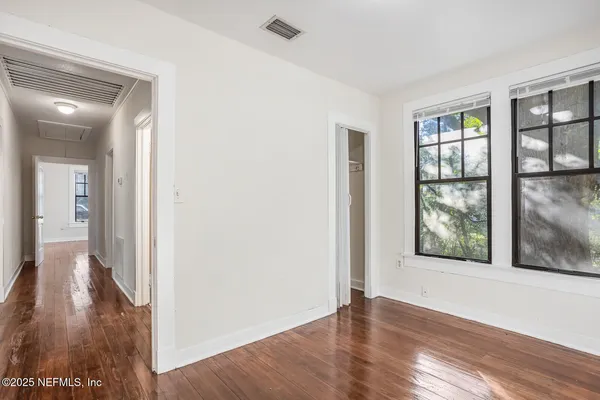 a view of a hallway with wooden floor and windows