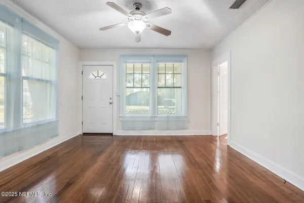 an empty room with wooden floor and windows
