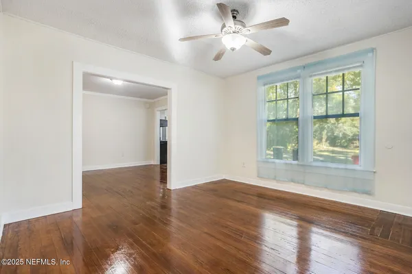 a view of an empty room with wooden floor and a window