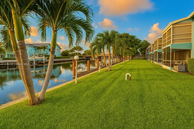 a view of a swimming pool with a yard and palm trees