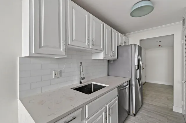 a kitchen with stainless steel appliances granite countertop a sink a stove a refrigerator and island with wooden floor