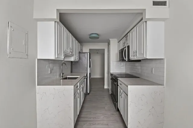 a kitchen with stainless steel appliances granite countertop a stove a sink and a microwave